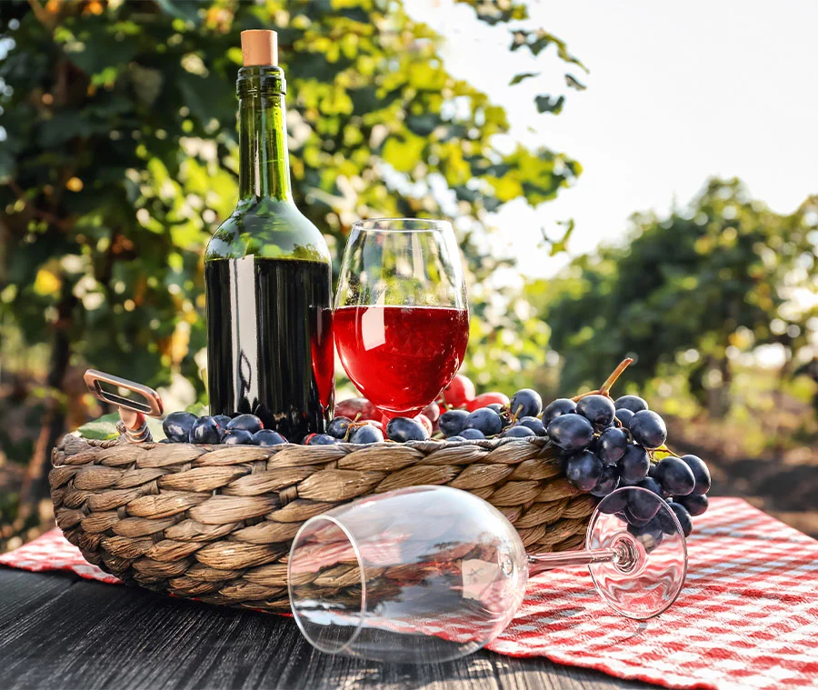 Photo d'une bouteille de vin avec verre et corbeille rempli de raisin